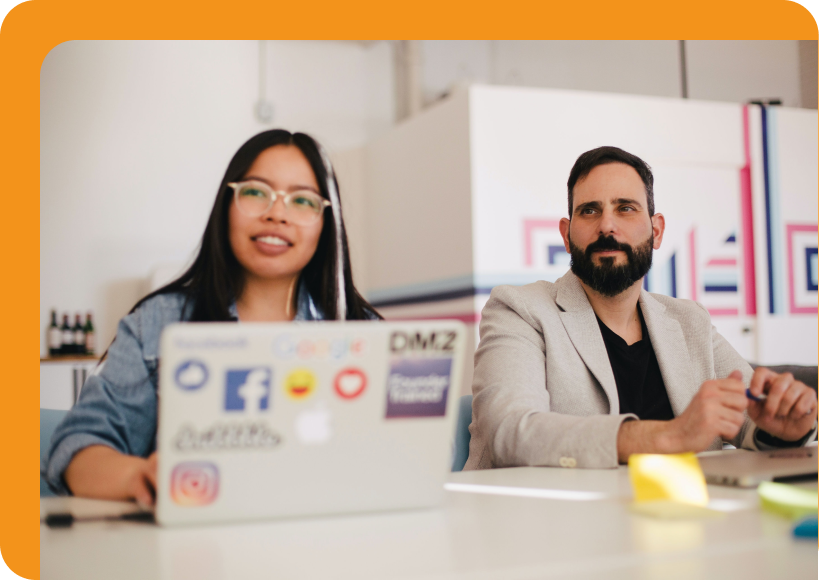 Diverse team members engaged in a collaborative discussion, with a laptop displaying social media stickers, emphasizing teamwork and innovative solutions for employee recognition and performance enhancement.
